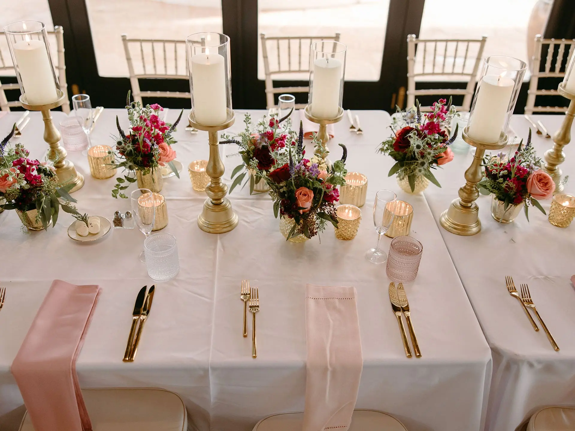 Elegant long banquet table adorned with gold candlesticks, romantic floral arrangements, and soft pink linens at the Lakeside Ballroom at The Red Berry Estate wedding.
Photo: Jessie Schultz Photography