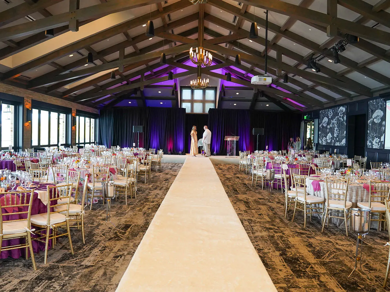 A spacious wedding reception hall in the lakeside ballroom of Red Berry Estate, illuminated with soft purple lighting, creating a romantic and festive atmosphere.