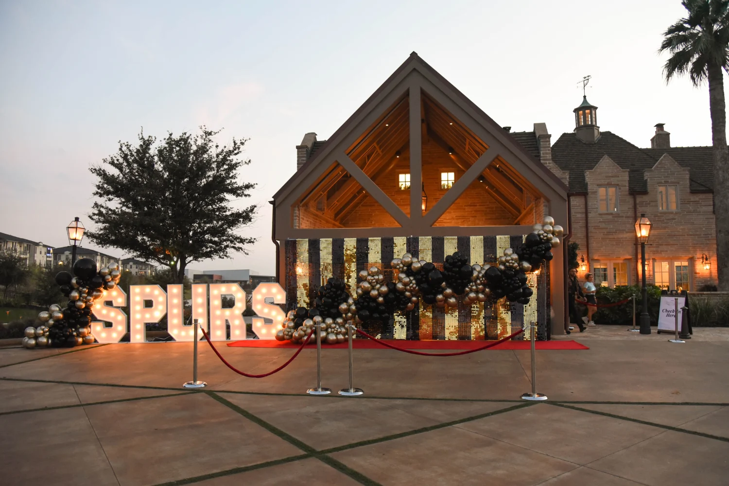 The entrance of The Red Berry Estate decorated with gold pillars, black and gold ballons and light up letters spelling SPURS