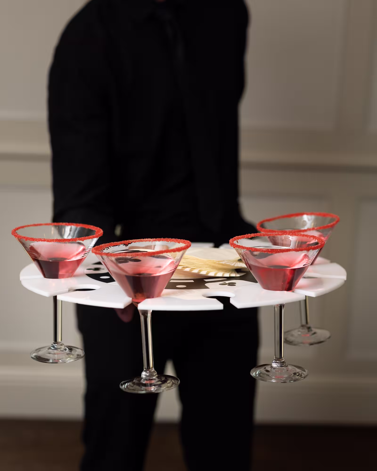 Server carrying drinks in margarita glasses with red coated rims