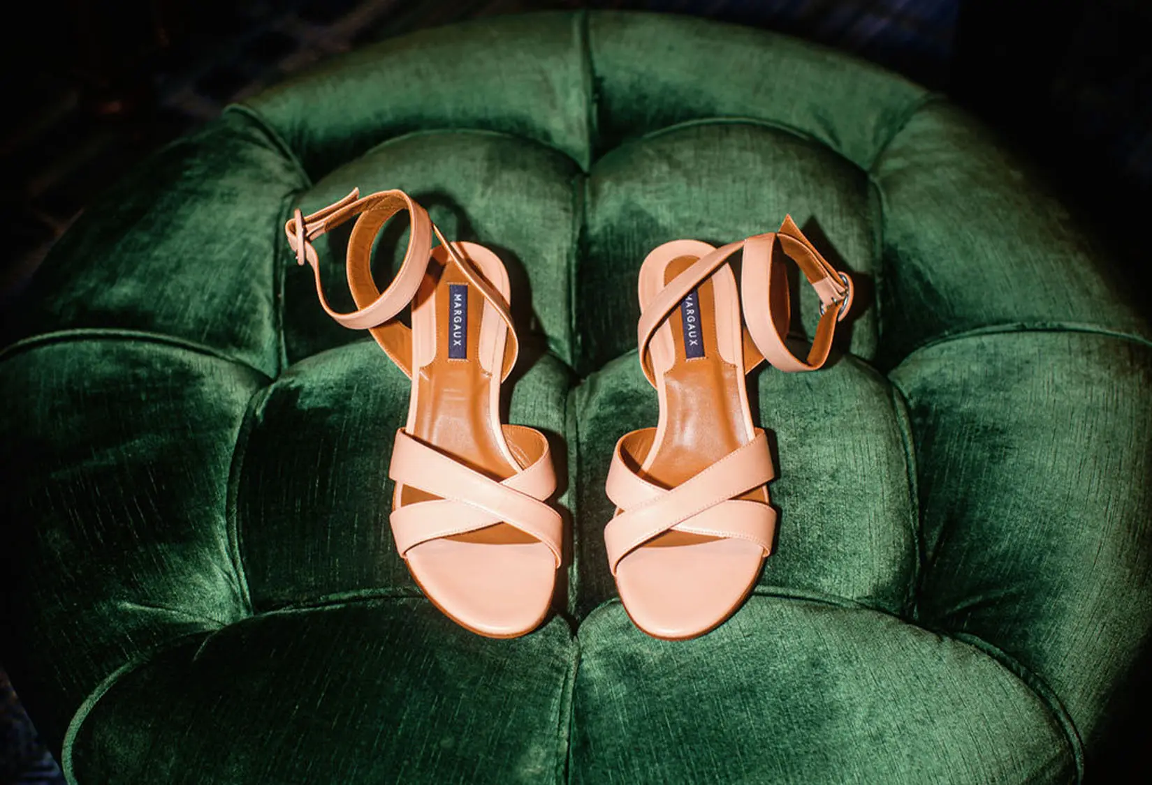 Blush strappy bridal heels displayed on a plush green velvet ottoman in the Chateau of The Red Berry Estate Mansion, showcasing bridal details.
Credit: Joseph West Photography