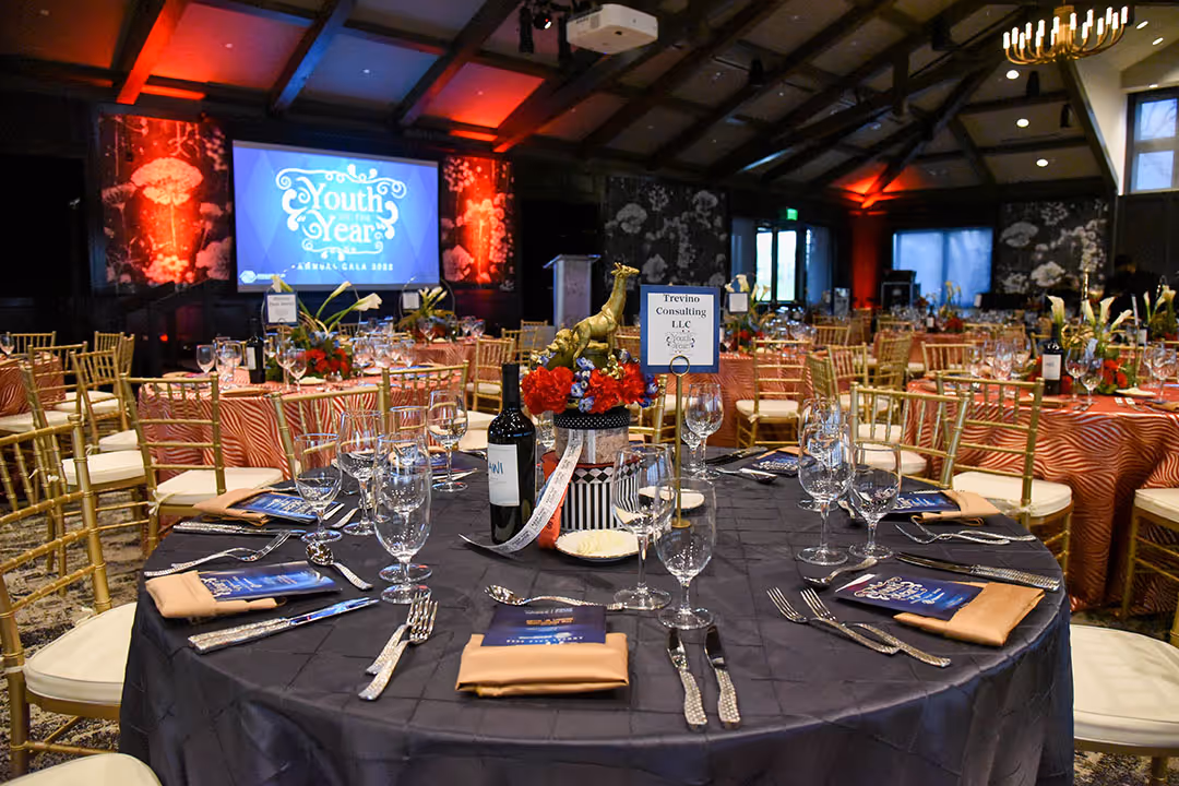 Event at The Red Berry Estate for Boys & Girls Club, showing a large room with a projected image on the wall, many tables set for dining.