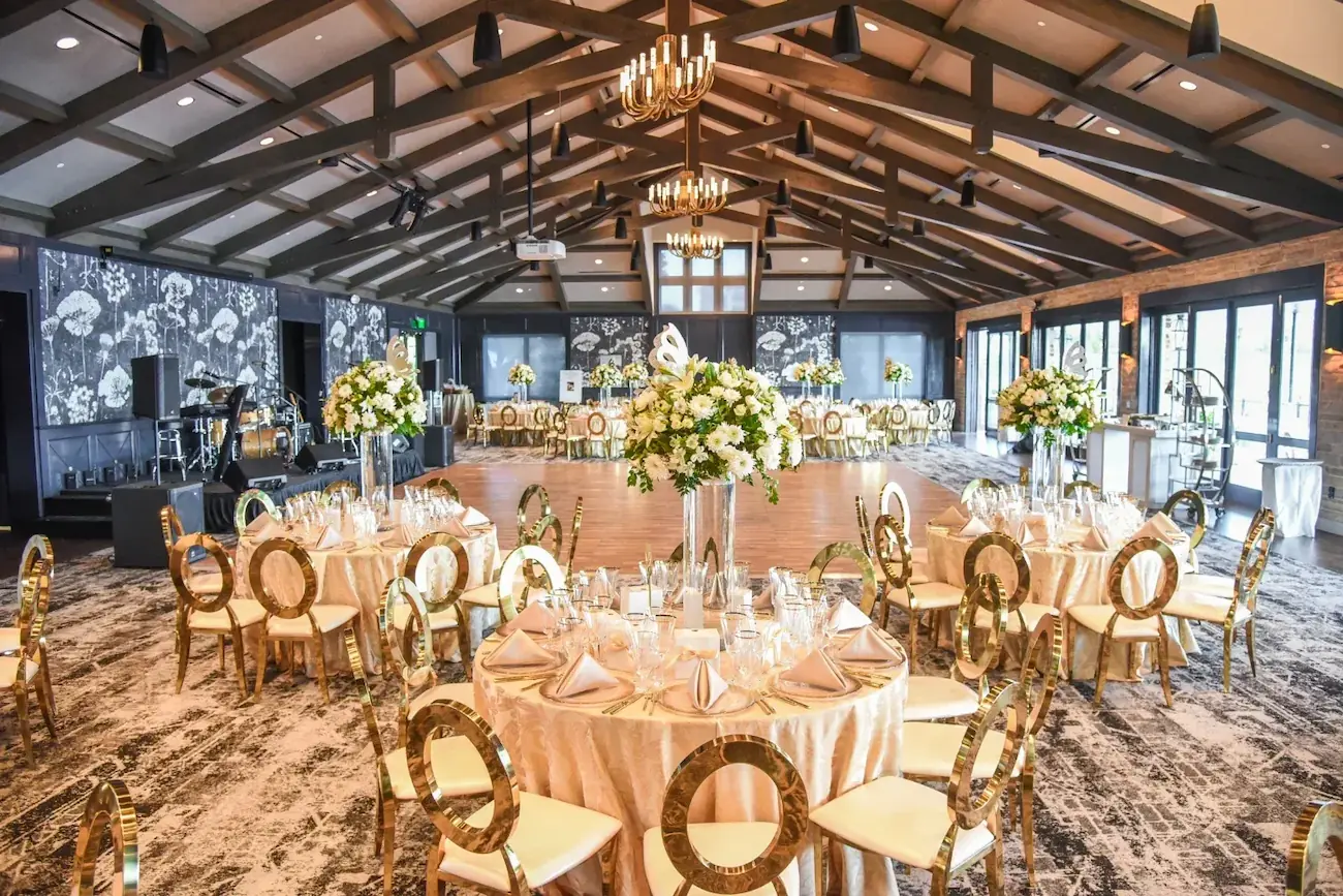 Wide view of even tables at The Red Berry Estate Ballroom decorated with light colors, gold and butterflies