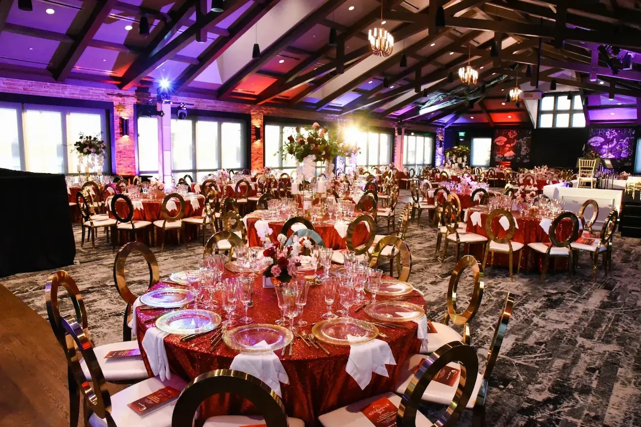 Wide view of even tables at The Red Berry Estate Ballroom decorated with reds and golds