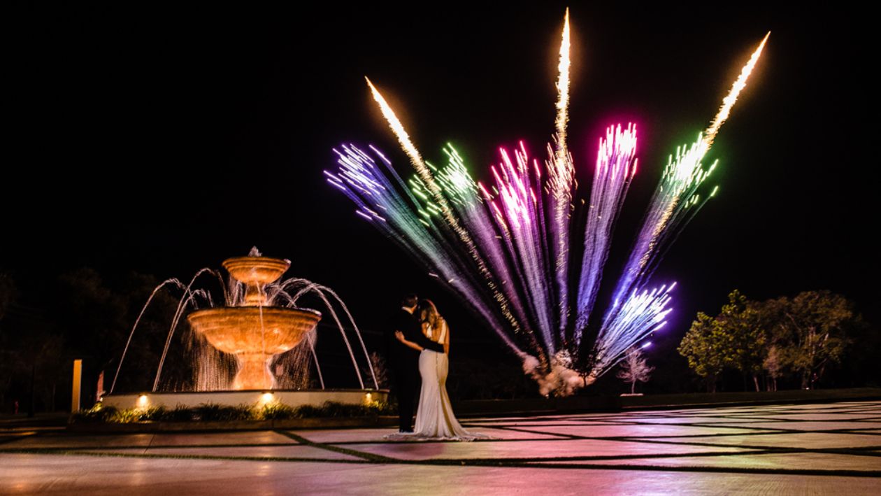 Couple standing by front fountain watching fireworks