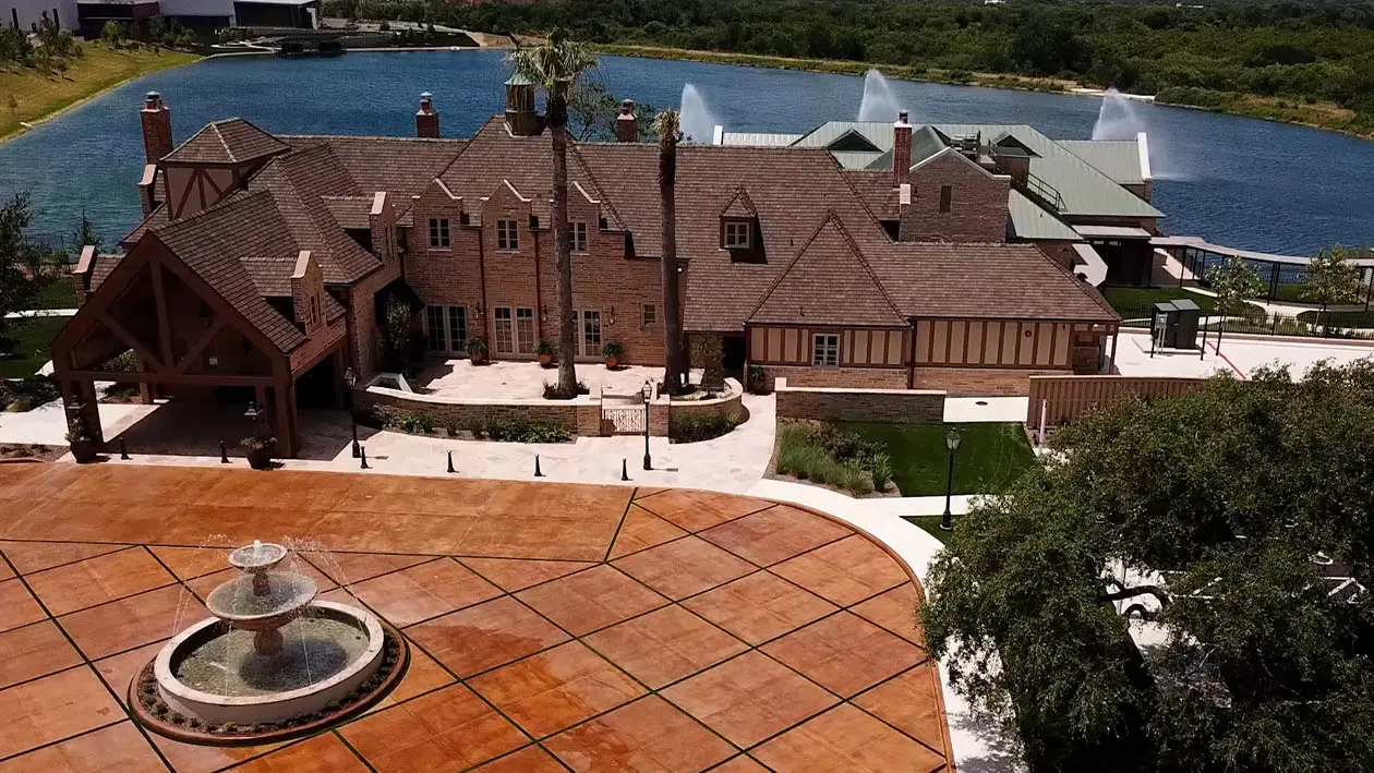 Drone shot of The Red Berry Estate with a decorative fountain in front, showcasing elegant architecture and landscaping.