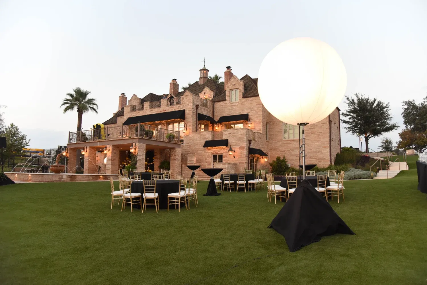 tables and lights set up on the back lawn of the red berry estate