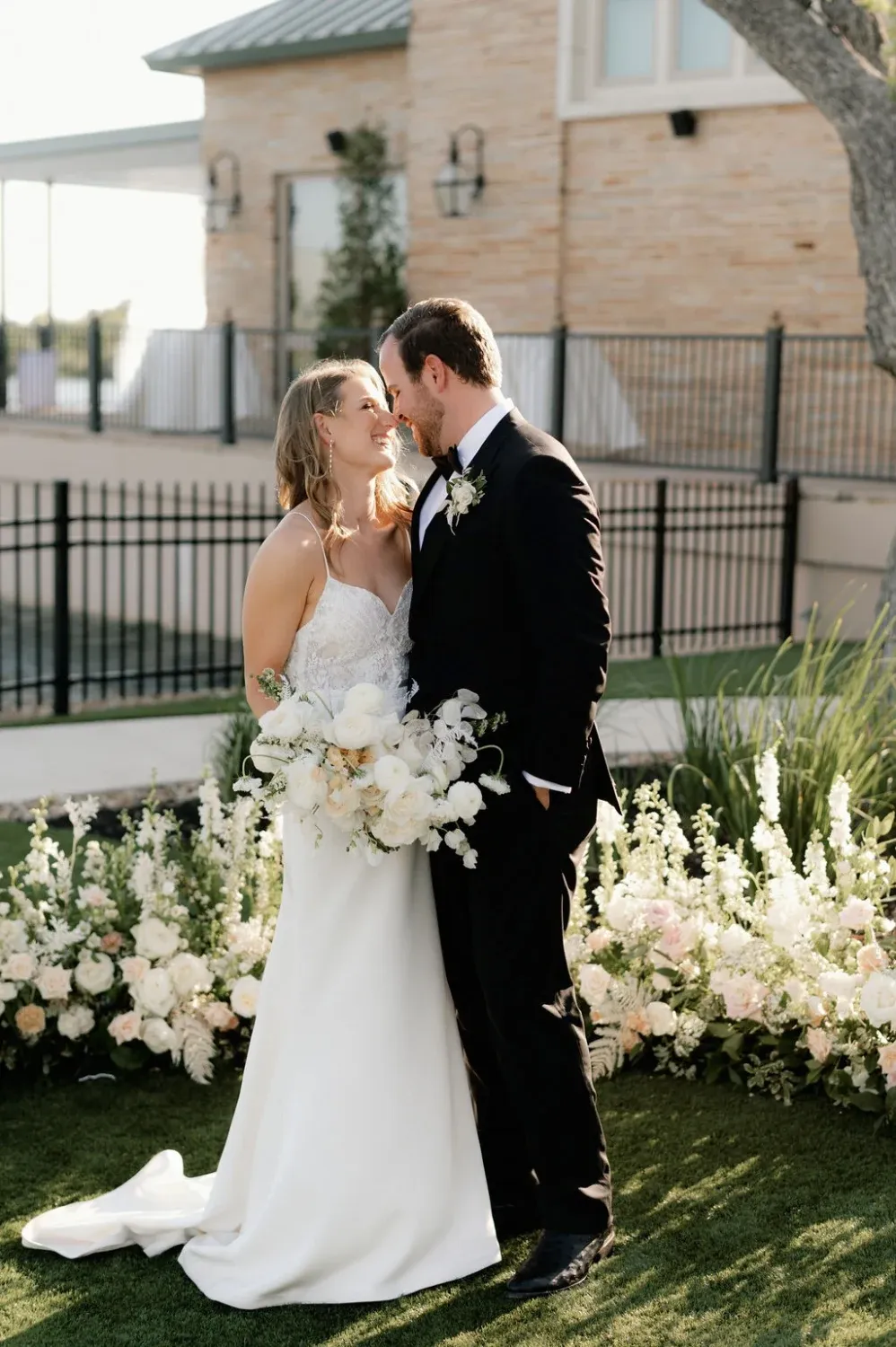Bride and groom standing together during an outdoor wedding ceremony at The Red Berry Estate, surrounded by floral arrangements.
